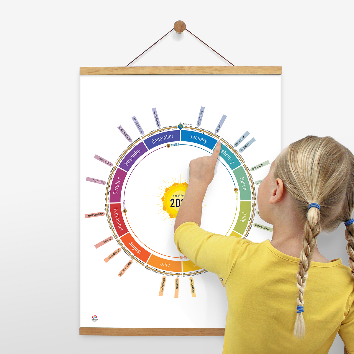 Child using the White Year Round Calendar to count down days until their birthday. Displayed on the wall with a wooden poster hanger.